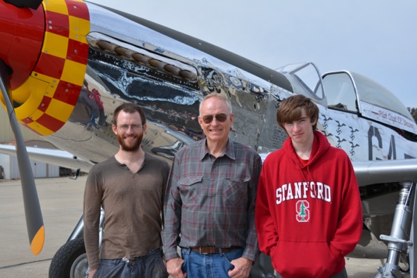Netapp cofounder Michael Malcom flanked by two people standing in front of a P-51 Mustang airplane